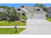 Charming home with lush landscaping, a well-manicured lawn, and a spacious driveway at 2919 Northfield Dr, Tarpon Springs, FL 34688