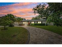Charming single-story home featuring a lush front yard, paver driveway, and beautiful landscaping at sunset at 8231 31St N Ter, St Petersburg, FL 33710