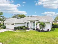 Beautiful single-story home featuring manicured landscaping, light exterior, and a well-maintained lawn at 8804 Poe Dr, Hudson, FL 34667