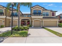 Beautiful townhome with a two-car garage, a well-manicured lawn, and a beautiful palm tree at 11442 Crowned Sparrow Ln, Tampa, FL 33626
