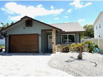 Charming single Gathering home with stone accents, decorative gravel, and a well-manicured lawn at 1165 Falcon Dr, Dunedin, FL 34698