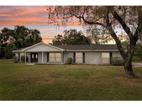 Charming single-story home featuring a well-manicured lawn and a classic brick facade at sunset at 1226 Debuel Rd, Lutz, FL 33549