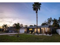 Charming single-story home featuring a well-manicured lawn, lush landscaping, and inviting front porch at dusk at 3981 Mckay Creek Dr, Largo, FL 33770