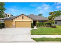 Charming single-story home featuring a manicured lawn and a two-car garage, perfect for suburban living at 4725 Royal Birkdale Way, Wesley Chapel, FL 33543