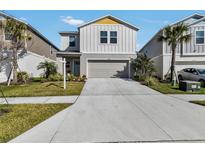 Charming two-story home featuring a well-manicured lawn, two car garage, and inviting light blue front door at 5486 Summer Sunset Dr, Apollo Beach, FL 33572