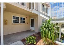 Exterior shot of condo with a white door, walkway, plants, and outdoor staircase leading to the second floor at 10035 63Rd N Ave # 12, St Petersburg, FL 33708