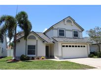 Charming two-story home featuring a well-manicured lawn, two-car garage, and lush palm trees at 10906 Kenbrook Dr, Riverview, FL 33578