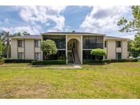 Low-angle view of the neutral-toned exterior of this two-story condominium building with lush landscaping and a central staircase at 1400 Pine Glen Ln # B2, Tarpon Springs, FL 34688
