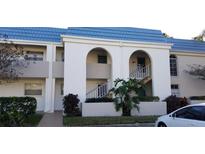 Charming condo building featuring a distinctive blue roof and well-maintained landscaping at 1975 W Bay Dr # 207, Largo, FL 33770