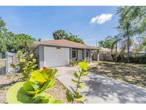 Charming single-story home with a well-maintained lawn, mature trees, and a driveway leading to the garage at 3208 E 8Th Ave, Tampa, FL 33605