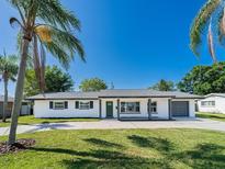 Charming single-story home with a well-manicured lawn and beautiful landscaping featuring mature palm trees at 352 79Th Ne Ave, St Petersburg, FL 33702