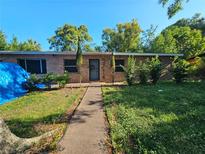 Charming brick home featuring a walkway, well-maintained landscaping and dark front door at 3714 E Ellicott St, Tampa, FL 33610