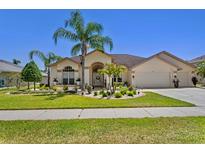 Charming home featuring well-manicured landscaping, a two-car garage, and a welcoming entrance at 5113 Epping Ln, Zephyrhills, FL 33541