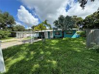 Charming blue home featuring a well-maintained lawn and beautiful palm trees in the front yard at 6047 67Th N Ave, Pinellas Park, FL 33781