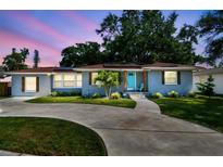 Charming home featuring a well-maintained front yard, circular driveway, and a bright blue front door at 6207 Gulfport S Blvd, Gulfport, FL 33707