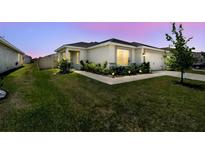 Charming home with lush landscaping, featuring a well-manicured lawn and garden beds, highlighted by walkway lighting at 105 Blue Alice Spring Ct, Ruskin, FL 33570