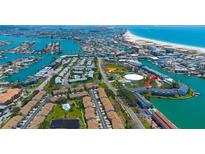 An aerial view showcases a bayside neighborhood with a pool, docks, and residential buildings at 12140 Capri S Cir, Treasure Island, FL 33706