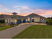 Beautifully designed home featuring a manicured lawn, stone accents, and a spacious three-car garage at 13805 Carryback Dr, Dade City, FL 33525