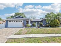 Charming one-story home with a well-manicured front yard, beautiful landscaping, and a brick driveway at 206 Timberview Dr, Safety Harbor, FL 34695