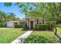 Charming single-story home with a well-manicured lawn, lush landscaping, and decorative shutters and front door at 219 Park S Cir, Dunedin, FL 34698