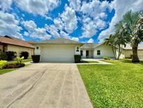 Charming single-story home featuring a two-car garage, landscaped yard, and welcoming curb appeal under a beautiful sky at 3944 102Nd N Pl, Clearwater, FL 33762