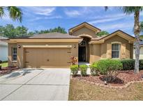 Beautiful single Gathering home featuring a two-car garage, neat landscaping and tan-colored exterior at 4500 Fieldview Cir, Wesley Chapel, FL 33545