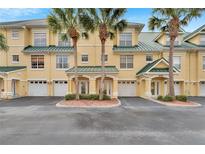 Inviting yellow townhouses feature attached garages, private entrances, and neatly trimmed landscaping with beautiful palm trees at 6414 Sunset Bay Cir, Apollo Beach, FL 33572