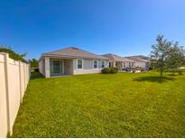 View of the grassy backyard and exterior of the home with white fence at 10729 Planer Picket Dr, Riverview, FL 33569