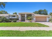 Beautiful single-story home with a well-manicured lawn, mature landscaping, and a two-car garage at 13553 Glaze Brook Dr, Hudson, FL 34667