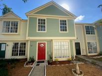 Charming two-story townhouse featuring a red door, neutral siding and well-maintained landscaping at 13909 Fletchers Mill Dr, Tampa, FL 33613