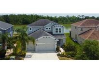 Beautiful two-story home with a two-car garage, situated near a pond and lush green trees at 33176 Whisper Pointe Dr, Wesley Chapel, FL 33545