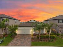 Charming single-Gathering home with a two-car garage, paver driveway, and lush landscaping at 5059 Bromeliad Ave, Wimauma, FL 33598