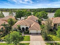 Stunning waterfront home with a tile roof, lush landscaping, and a spacious driveway at 9630 Tree Tops Lake Rd, Tampa, FL 33626