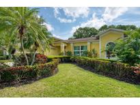 Lush front yard with manicured hedges and palms leading up to a bright yellow single-Gathering home at 10321 Shady Oak Ln, Seminole, FL 33777