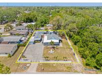 Aerial view of the home featuring a fenced yard, two buildings, tropical landscaping, and parking at 1322 Idlewild Dr, Clearwater, FL 33755