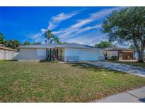 Charming single-Gathering home featuring a well-maintained lawn, a two-car garage, and beautiful landscaping at 1710 Hibiscus N Cir, Oldsmar, FL 34677