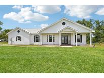 Charming one-story home featuring a metal roof, covered porch, green grass and black shutters at 21019 Lonesome Acre Rd, Wimauma, FL 33598