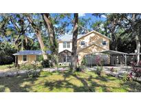 Charming two-story home with lush landscaping, screened porch, and carport at 315 Wooten Rd, Lutz, FL 33548