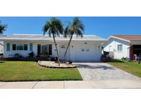 Charming single-story home with a well-maintained lawn, palm trees and brick-paved driveway at 3436 100Th N Ave, Pinellas Park, FL 33782