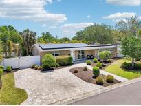 Well-maintained single-story home featuring a brick driveway, lush landscaping, and solar panels on the roof at 4091 Cherry Ne St, St Petersburg, FL 33703