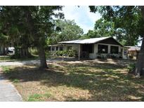 Charming single-story home with a covered front porch and mature trees surrounding the property at 601 W College Ave, Ruskin, FL 33570