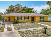 Charming yellow single-story home featuring dark shutters, a brown roof, and a well-kept yard at 7280 Tarrytown Dr, Spring Hill, FL 34606