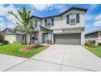 Two-story home with gray siding, a two-car garage, neat landscaping and an American flag at 754 8Th Nw St, Ruskin, FL 33570