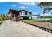 Coastal home featuring a raised foundation, screened porch, and a spacious driveway at 9118 Brunswick Ln, Tampa, FL 33615