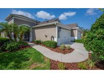 Charming home with a two-car garage, blue door, and lush landscaping at 13611 Circa Crossing Dr, Lithia, FL 33547