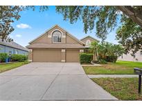Charming two-story home featuring a three-car garage, manicured lawn, and mature landscaping at 16119 Bridgedale Dr, Lithia, FL 33547