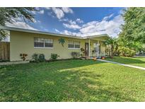 Charming single-story home with a well-maintained lawn, complemented by lush landscaping and mature trees at 208 44Th Ne Ave, St Petersburg, FL 33703