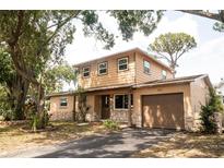 Two-story home with stone accents, attached garage, mature trees and an asphalt driveway at 771 Murphy N Ave, St Petersburg, FL 33703