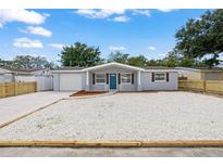 Charming single-story home featuring a minimalist landscape, garage, and blue accent door at 1427 Gerard Ln, Holiday, FL 34690