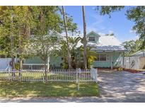Charming bungalow with white picket fence, lush tropical landscaping, and a metal roof at 2014 E Broad St, Tampa, FL 33610